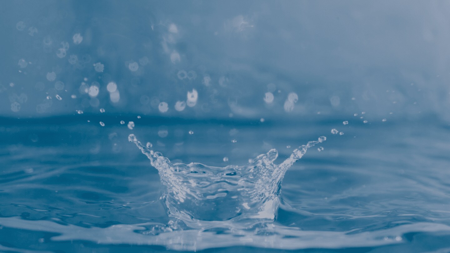 An image capturing the moment a water droplet splashes across clear blue water.