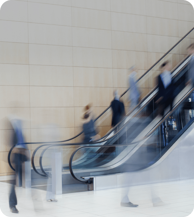 People moving busily using the escalators inside the building.