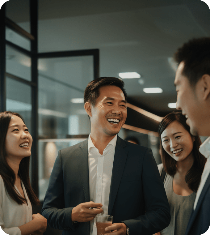 明るいオフィスでビジネスの服装をした人たちが一緒に笑いながら会話している様子です。