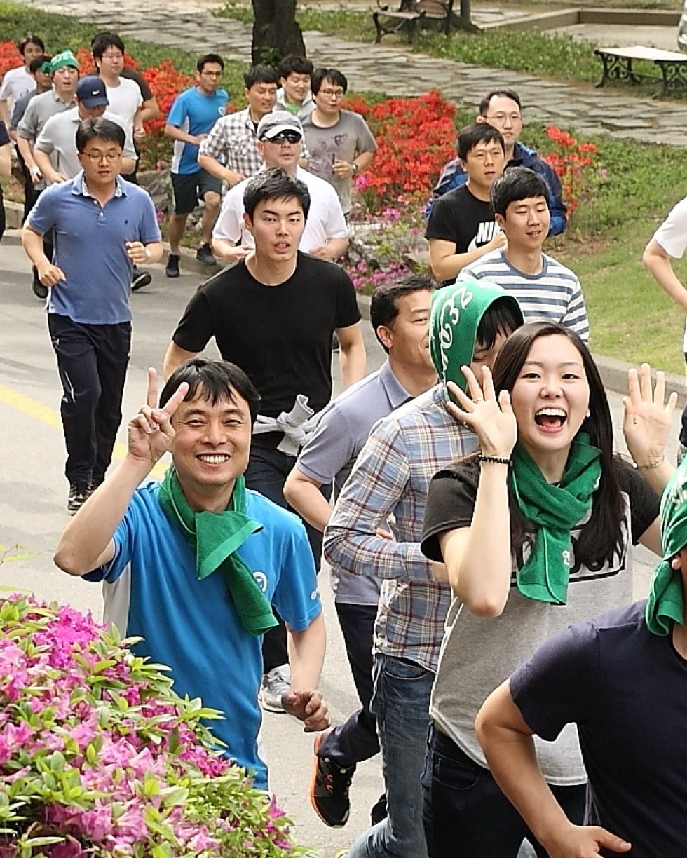 A group of people are smiling as they're jogging.